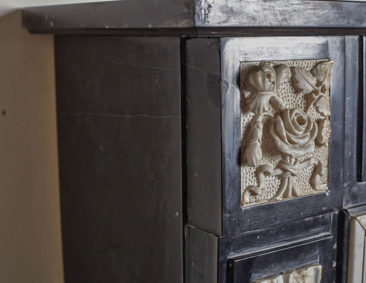 Marble mantel has carved center panel that portrays a serpent wrapped urn in addition to foliage. Side panels incorporate rings and tassels.